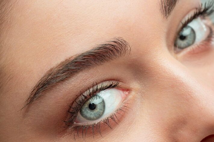 Naheaufnahme eines Gesichts mit betonten Augenbrauen und strahlend blauen Augen.